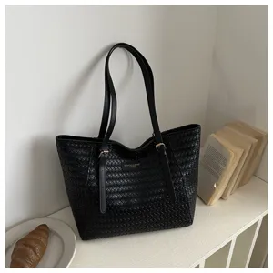Vista detallada del bolso tote de cuero PU tejido negro que muestra textura y elegantes correas.