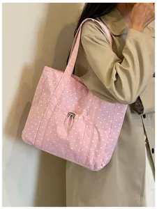 Primo piano dettagliato della borsa shopper in tessuto a pois rosa indossata dalla modella.