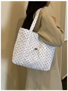 Vista di dettaglio della borsa tote a spalla in tela bianca con classico motivo a pois neri.