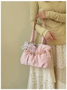 Dettaglio della borsa a spalla rosa a pois con grazioso fiocco e ciondolo di perle.
