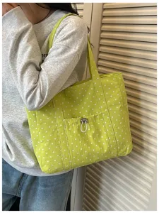 Vista dettagliata della borsa tote in tela a pois verde chiaro con tasca frontale.