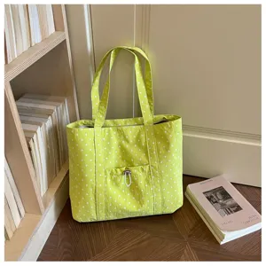 Dettaglio borsa shopper in tela a pois verdi, con tasca frontale per stile casual quotidiano.