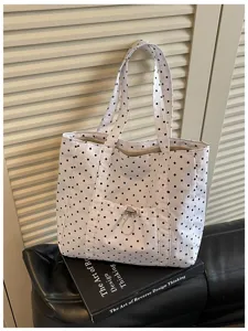 Vista dettagliata della borsa tote in tela bianca con pois neri e comoda tasca frontale.