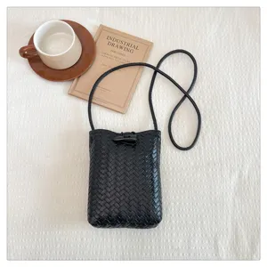 Detailed view of black woven PU leather crossbody phone bag with horn button decoration.