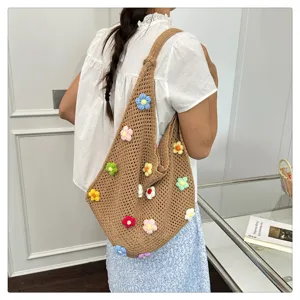 Sac bandoulière au crochet fait main avec des applications de fleurs pour un look quotidien.