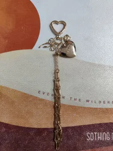 Gold metal heart keychain handbag pendant detailed view, stylish bag charm and accessory.