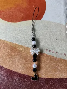 Detail view of a Korean style sweet pearl bow phone charm with black and white beads.