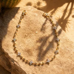 Gros plan de la chaîne de pantalon dorée à perles avec pendentifs quatre étoiles strass.