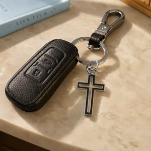 Elegante estuche de cuero negro para llaves de auto con llavero colgante de cruz hueca.