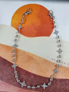 Vue de détail de la chaîne de pantalon Y2K strass étoile et perles métalliques accessoire.