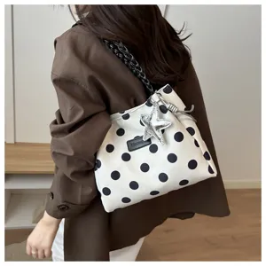 Vista di dettaglio della borsa tote elegante a pois neri e bianchi con ciondolo a stella.
