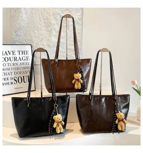Vista dettagliata della borsa tote retrò minimalista con grazioso ciondolo orsetto e nappa.
