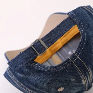 Dettaglio cappellino da baseball in denim con fibbia metallica regolabile e cuciture rifinite.