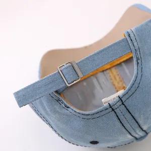 Primo piano dei dettagli del berretto di jeans con fibbia metallica regolabile e cuciture.