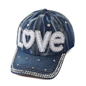 Primo piano del berretto in denim con lettere LOVE in perle e strass scintillanti.
