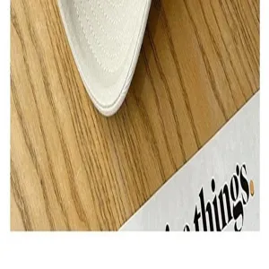 Detail of cotton baseball cap brim, showing fine stitching on wooden desk background.