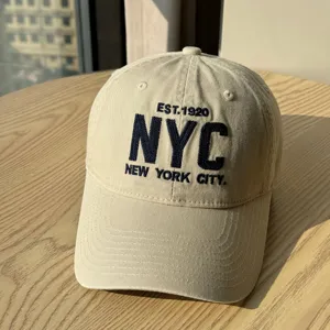 Detail view of casual beige cotton baseball cap with NYC embroidered letters, soft crown design.