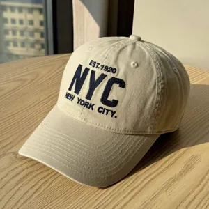 Close-up detail of beige casual soft-top baseball cap with NYC embroidered letters.