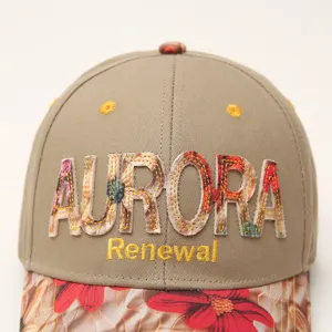 Detailed close-up of khaki baseball cap featuring floral applique and embroidered letters.
