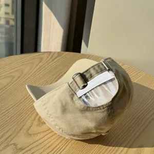 Detail view of a casual beige soft top baseball cap with adjustable metal buckle strap.