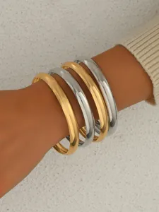 Vue détaillée de bracelets rigides empilables en métal mixte, dorés et argentés lisses.