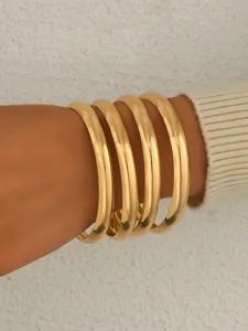 Ensemble de quatre bracelets jonc rigides en metal dore lisse style minimaliste chic