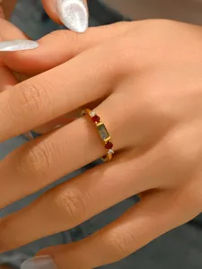 Close-up detail of the vintage copper ring with green stone and red diamonds on hand.