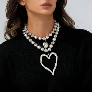 Layered chunky silver bead necklace with abstract heart pendant fashion jewelry detail shot