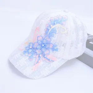 Close-up detail of white lace baseball cap with blue pink floral embroidery and pearl accents.