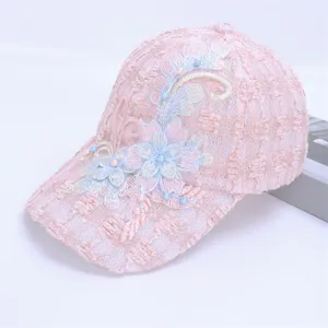 Close-up of pink lace baseball cap with floral embroidery and elegant pearl accents.