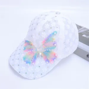White lace baseball cap detail showing pastel mesh bow and sparkling rhinestone decorations.