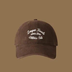 Detail view of the brown baseball cap featuring white embroidered athletic club lettering.
