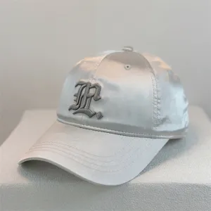 Close-up of the smooth satin baseball cap featuring delicate gothic letter embroidery detail.