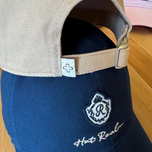Detailed view of casual embroidered baseball cap with adjustable strap and crest logo.