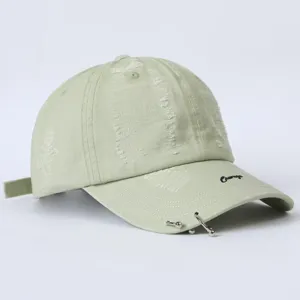 Detailaufnahme der hellgrünen Distressed-Baseballcap mit Metall-Piercingringen und cooler Stickerei.