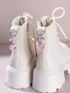 Gedetailleerd aanzicht van beige plateau-laarzen met schattige roze kristallen hart-hangers.