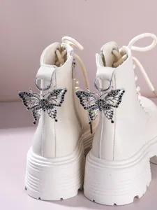 Detailed view of white platform Martin boots featuring intricate hollow black rhinestone butterfly charms.