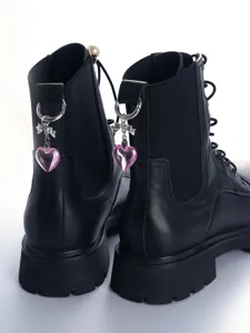 Detailopname van zwarte leren laarzen met leuke roze kristallen hartje bedels.