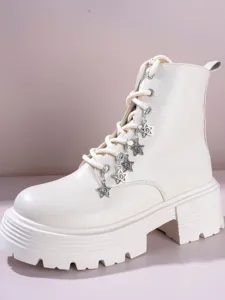 Detail shot of white platform combat boots featuring punk style metal star charms and lace-up design.