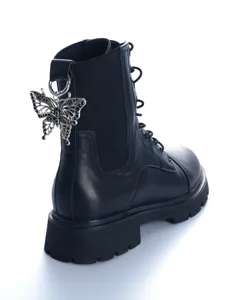 Detail view of black martin boot featuring a gothic silver hollow butterfly pendant charm.