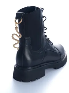 Close-up detail of black leather combat boot heel with gold snake charm accessory.