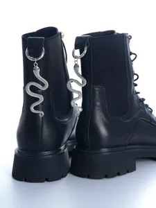 Close-up detail of gothic black leather combat boots featuring metal snake pendant on the heel pull.