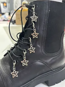 Close-up detail of gothic punk metal star charms attached to black leather boot laces.