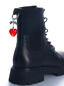 Close-up detail van zwarte leren bikerboot met rode kristallen hart en strik hanger charm.