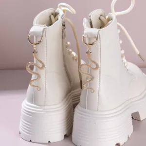 White platform combat boots featuring a gold snake charm, trendy punk style lace-up booties.