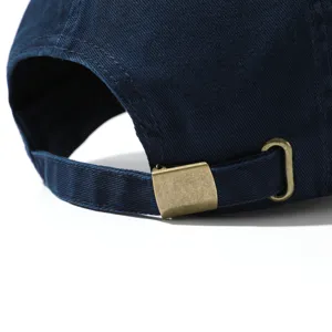 Close-up detail of the metal adjustable buckle on the back of a navy blue baseball cap.