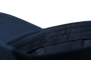 Close-up detail of navy blue baseball cap stitching, premium fabric texture and craft.