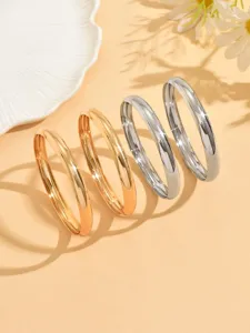 Détail de bracelets rigides métalliques lisses, design géométrique doré argent.