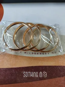 Vue détaillée de joncs ronds en métal doré lisse minimaliste, bracelet géométrique élégant.