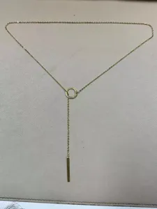 Gold tone lariat necklace detail, showcasing a delicate chain with a circle and bar pendant.